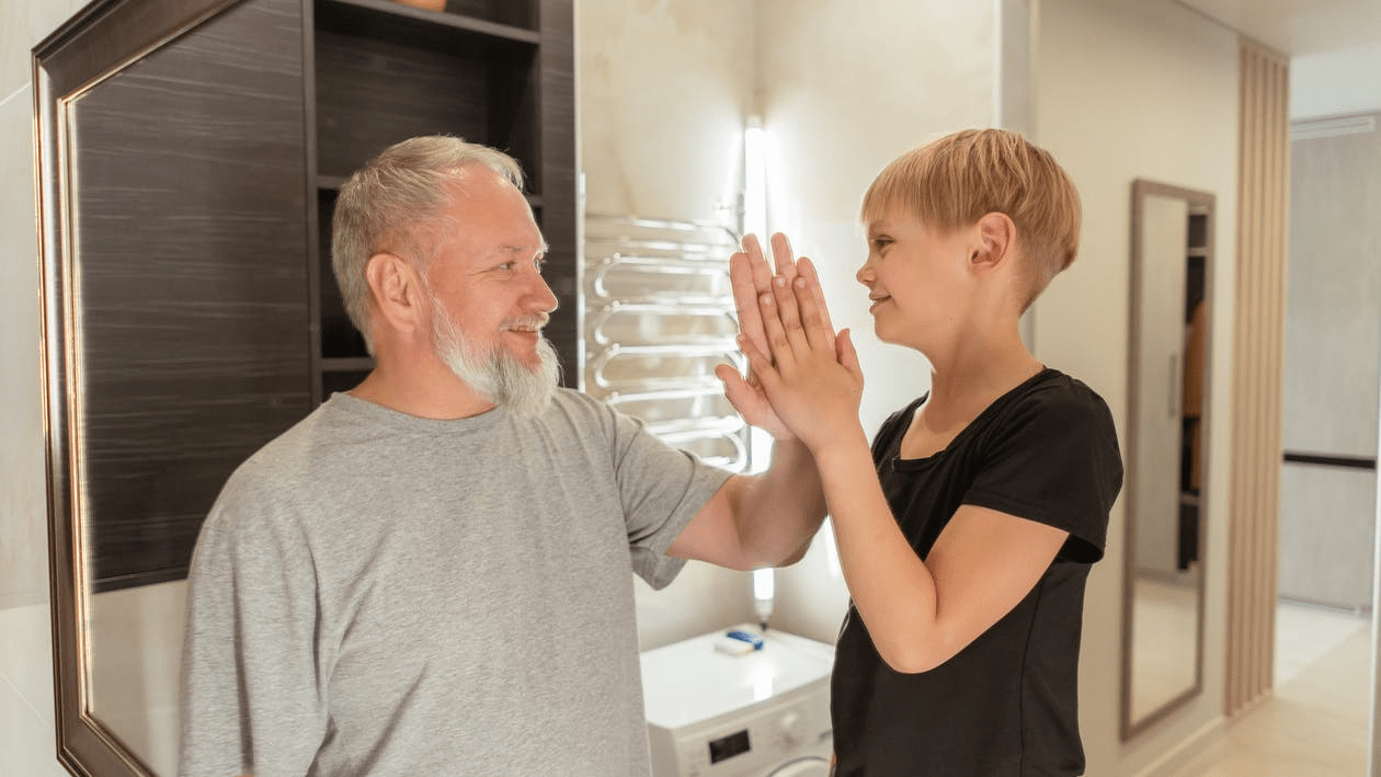 A grandfather high-fiving his granddaughter in the bathroom